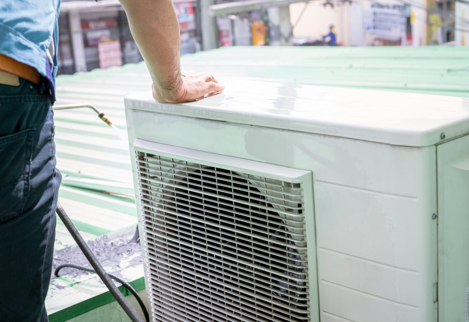 Condensing unit of an air conditioner on blur technician spraying